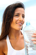 Portrait of attractive woman holding bottle of water outside