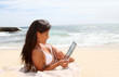 Beautiful woman in bikini using tablet on the beach
