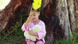 Smiling girl playing with a flower and a teddy bear