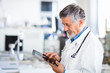 Senior doctor using his tablet computer at work