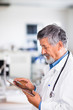 Senior doctor using his tablet computer at work
