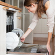 Housework: young woman putting dishes in the dishwasher