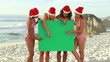 Four girls wearing christmas hats at the beach