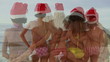 Four girls embracing each other while wearing santa hats