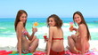 Three women sitting on towels on the sand