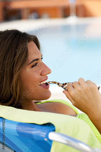 Photo: Woman lying on deckchair by swimming-pool Woman lying on deckchair by swimming-pool
