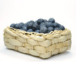 Blueberries in a straw basket on a white background