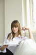 Young woman reading magazine, holding glasses