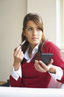 Young woman applying blusher with brush, contemplating