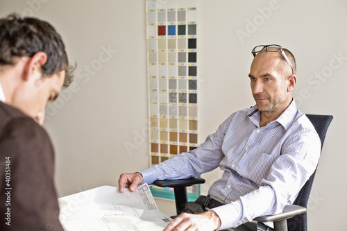 Photo: Businesspeople looking at blueprint in office Businesspeople looking at blueprint in office