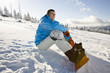 Young man sitting on snow, smiling, portrait