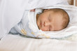 Baby sleeping on bed with red spots on face