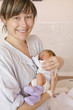 Mother carrying baby, smiling, portrait