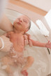 Woman giving bath to baby in bathtub