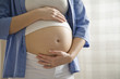 Pregnant woman with hand on belly, close-up