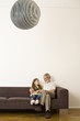 Senior man sitting with granddaughter on sofa