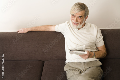 Photo: Senior man holding newspaper, smiling, portrait Senior man holding newspaper, smiling, portrait
