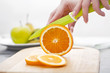 Woman's hands cutting fresh orange on kitchen Woman's hands cutting fresh orange on kitchen