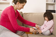 Woman adjusting daughter's shoe