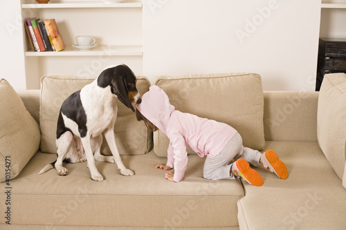 Photo: Child playing with dog in living room Child playing with dog in living room
