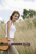 Mid adult woman holding guitar in field, portrait