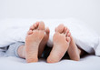 Feet of a couple under the blanket