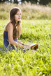 Mid adult woman holding book on field, portrait
