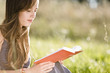 Foto: Mid adult woman reading book on field Mid adult woman reading book on field