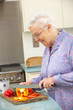 Senior woman chopping vegetables in domestic kitchen