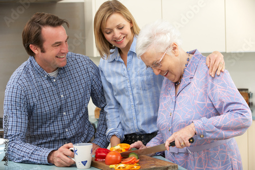 Photo: Senior woman and family preparing meal together Senior woman and family preparing meal together