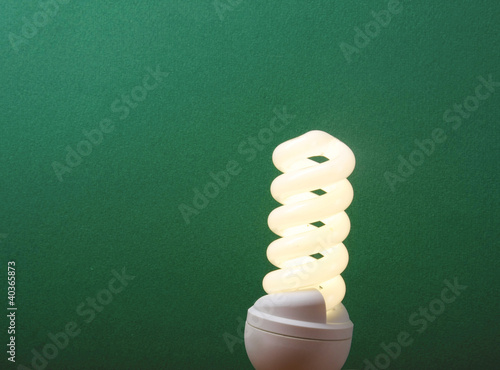 Photo: An energy-saving bulb, isolated on green An energy-saving bulb, isolated on green