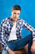 handsome young man with plaid shirt sitting on wood handsome young man with plaid shirt sitting on wood
