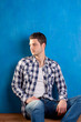 handsome young man with plaid shirt sitting on wood