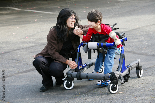 Photo: Mother with disabled son walking outdoors with walker Mother with disabled son walking outdoors with walker