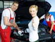 Mechanics works on engine bay, customer shows thumb up