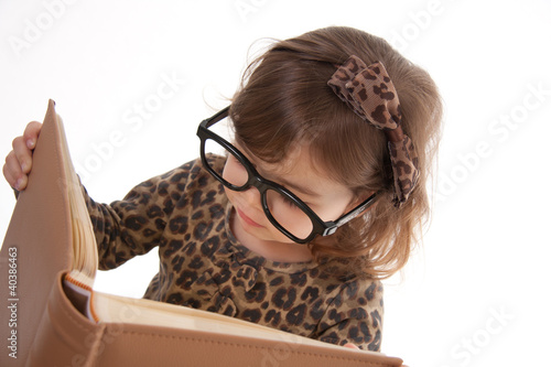 Photo: Child reading a book, wearing large glasses Child reading a book, wearing large glasses