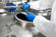 hands in gloves opening industrial process tank