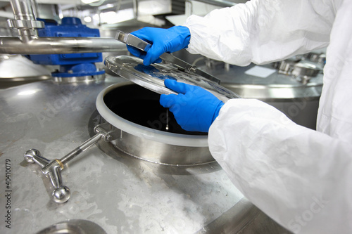 Foto: hands in gloves opening industrial process tank hands in gloves opening industrial process tank