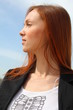 Pretty redhead young woman profile, with sky background