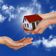 House and human hand against blue sky