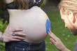 Young Man finger painting on a woman's pregnant belly