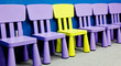 Yellow chair in the middle of several purple chairs