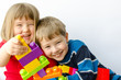 Two happy children play with blocks