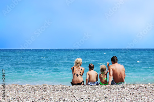 Photo: Family sitting back on beach Family sitting back on beach