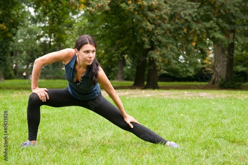 Photo: Woman performs stretching before sport in park Woman performs stretching before sport in park