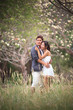 couples in wedding suit hug in blooming flowers garden