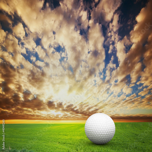 Photo: Playing golf. Ball on golf field at sunset Playing golf. Ball on golf field at sunset
