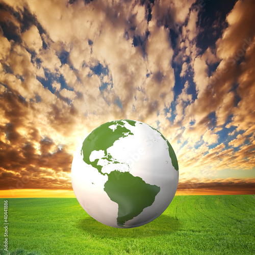Illustration: Planet Earth model on green field at sunset Planet Earth model on green field at sunset