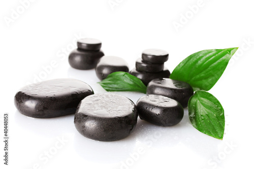 Photo: Spa stones with drops and green leaves isolated on white Spa stones with drops and green leaves isolated on white