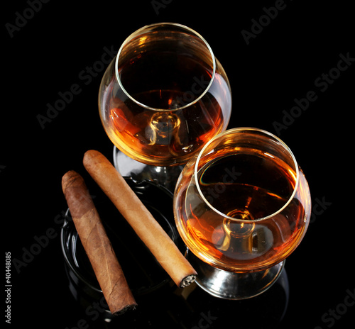 Photo: two glasses of brandy and cigars on black background two glasses of brandy and cigars on black background